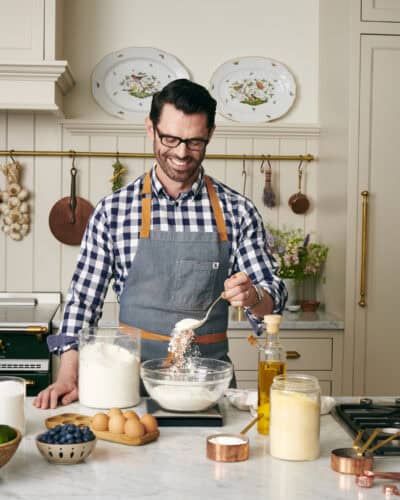Kitchen counter with mixing bowls, eggs, flour, and measuring tools arranged for baking